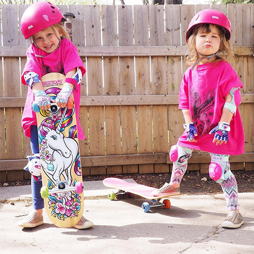 two girls in pink helmets with skatexs unicorn skateboards